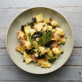 Photo of a plate of potato salad with olives, capers and dill