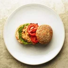 Photo of a white bean and potato burger on a bun with lettuce and tomato