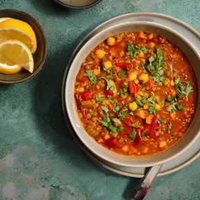 Plate of harissa soup with a bowl of lemon wedges