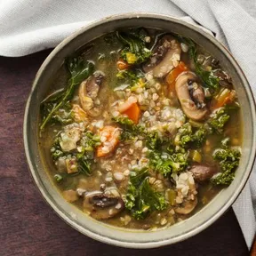 Photo of a bowl of clear mushroom soup, buckwheat and kale