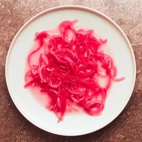 Photo of pickled red onion, spread out on a plate