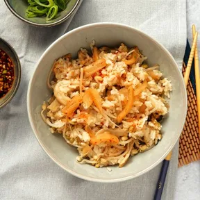 Een kom sushirijst met kimchi, tauge en oesterzwammen, met ernaast een kommetje pittige dressing