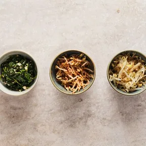 Photo of three bowls of Korean bapsang: 1 with spinach, 1 with spicy bean sprouts and 1 with mild bean sprouts