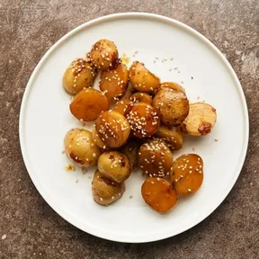 Photo of a plate of Korean potatoes smothered in soy sauce, garnished with sesame seeds