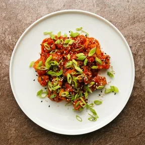 Foto van een bordje Koreaanse tofu met gochujangsaus, peer en lente-ui