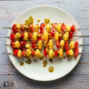 Photo of vegan bbq  skewers with gnocchi and bell pepper on a plate with pesto dressing