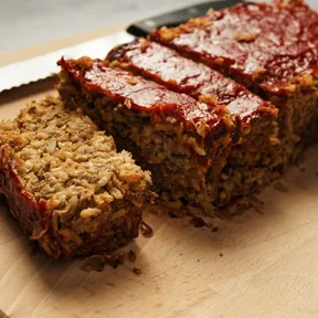 Foto van aangesneden linzenbrood met bruine rijst op een houten snijplank