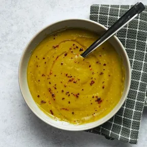 Photo of a bowl of Moroccan pea soup (bissara / tamarakt) garnished with olive oil and pul biber