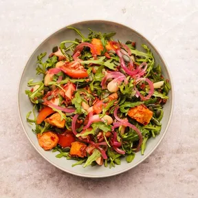 Een bord met rode rijst salade met pompoen en boterbonen