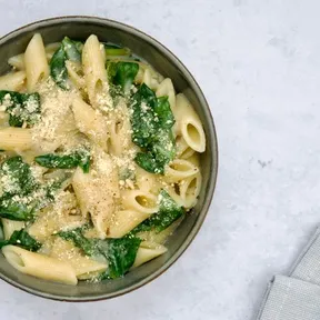 Bowl of penne with spinach and plant-based cream sauce