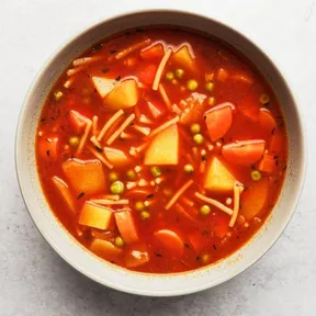 Photo of a bowl of simple tomato soup with carrots and peas