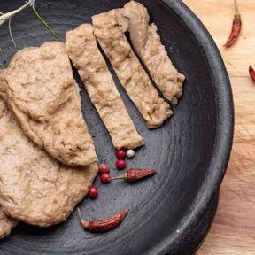 Stockfoto van seitan op een bord met wat pepertjes ernaast