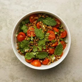 Photo of a bowl of lentil tabbouleh with cherry tomato, spring-onion and herbs. From recipe by Jamie Oliver.