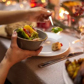 Foto van iemand die tijdens een kerstdiner groenten opschept