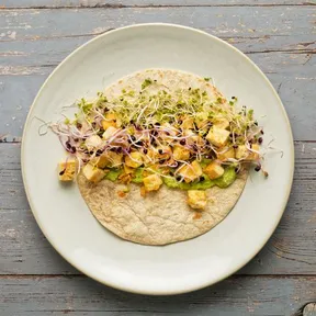 Unrolled wrap with baked tofu, sprouts and a spread of peas and horseradish